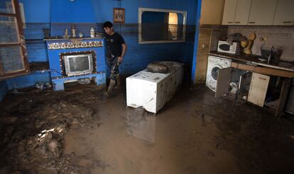 Un trabajador de las labores de limpieza anda por el fango en el interior de una de las viviendas arrasadas por la riada en Pueblo Laguna.