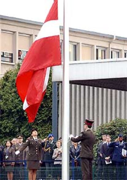 Dos soldados letones izan la bandera de su país en la sede de la OTAN en Bruselas.