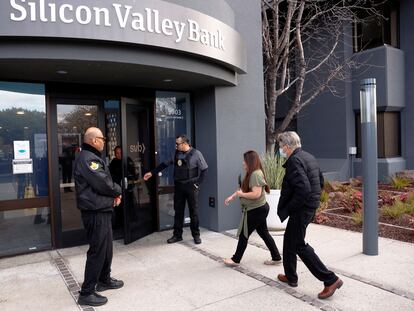 Policías escoltan clientes y trabajadores en una sucursal de Silicon Valley Bank.