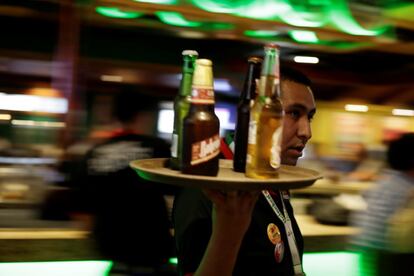 Un camarero lleva una bandeja con botellines de cerveza en un bar en Ciudad Juárez, México.