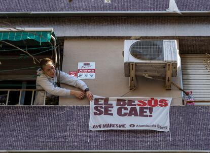 Una mujer que vive en un piso apuntalado de la calle Alfons el Magnànim coloca una pancarta en su fachada.