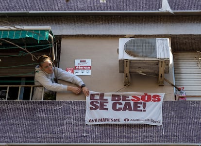 Una mujer que vive en un piso apuntalado de la calle Alfons el Magnànim coloca una pancarta en su fachada.