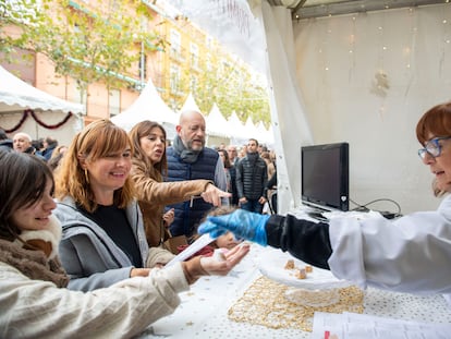 Una tendera ofrece a los clientes para degustar trozos de turrón de Alicante en la Feria de Navidad de Jijona.