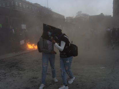 Mujeres se protegen en medio de la protesta a las afueras de Palacio Nacional.