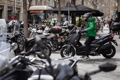 Un motorista sobre la acera tras encender su moto aparcada en la calle Casp de Barcelona.