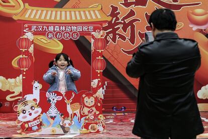 Un padre saca una foto a su hija mientras posa con la decoración del zoológico forestal de Jiufeng, en Wuhan (China).