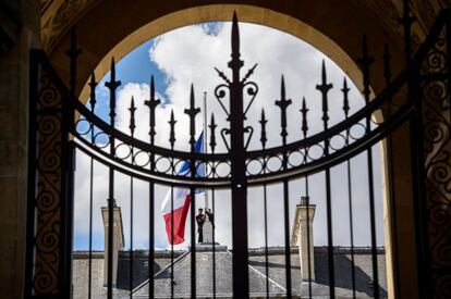 Una imagen tomada por la puerta muestra a dos guardias republicanos franceses colocando la bandera francesa a media asta en el palacio del Elseo en Pars, Francia