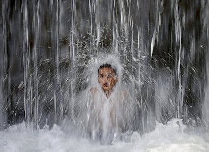 Un niño se baña bajo una cascada en Kabul (Afganistán).