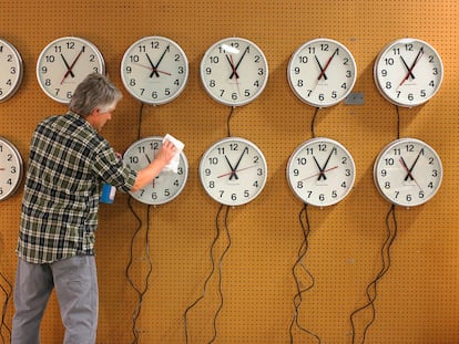 A man cleans the faces of wall clocks being tested at the Electric Time Company in Medfield, Massachusetts.