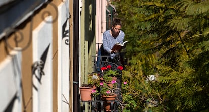 Una chica lee un libro en el balcon de su casa, durante el confinamiento por el virus covid-21, en Barcelona.