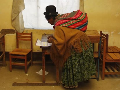 Una indígena boliviana marca la papeleta de votación del referéndum constitucional en un colegio electoral en El Alto (La paz)