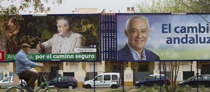 Un ciclista observa dos vallas electorales de José Antonio Griñán y Javier Arenas, el pasado sábado en Sevilla.