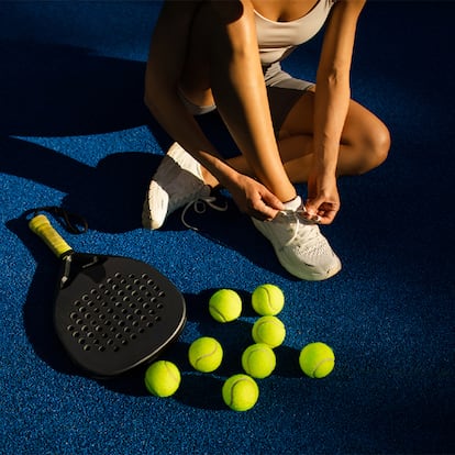 Una chica preparandose para jugar al pádel con pala y pelotas.