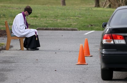 El reverendo Scott Holmer de la iglesia católica St. Edward confiesa a un creyente que se protege en su coche en Bowie, Maryland.