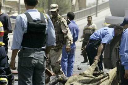 La policía retira el cadáver de una de las víctimas en un atentado con coche bomba ayer en Bagdad.