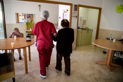 Una empleada ayuda a una señora mayor a caminar en la residencia de ancianos Santa María de Montecarmelo, en Madrid.