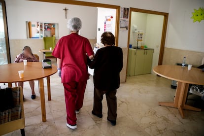 Una empleada ayuda a una señora mayor a caminar en la residencia de ancianos Santa María de Montecarmelo, en Madrid.