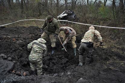 Varios agentes en el lugar donde el 8 de noviembre la explosión de una mina que pisó una excavadora (detrás, en la foto) acabó con la vida de tres empleados en una carretera de Chkalovske (región de Járkov)