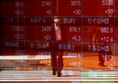 Un hombre se refleja sobre un panel de resultados de la Bolsa japonesa.