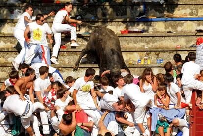 Unos mozos tiran del toro para evitar que alcance al público, que se agolpa al final de la grada.