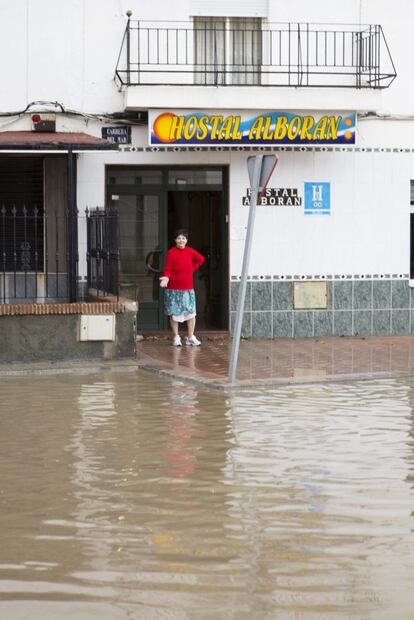 Una mujer en la puerta de su casa señala hasta donde ha llegado el agua tras la lluvia caída esta madrugada en la localidad granadina de Motril