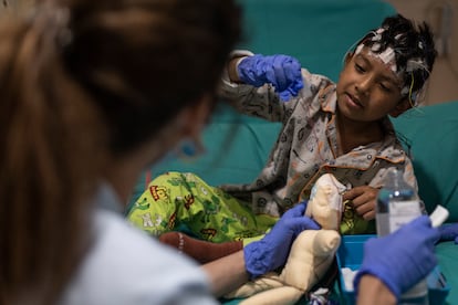 Sonia Tordera, coordinadora del programa Child Life del Hospital Sant Joan de Déu, explica su tratamiento con un muñeco a Eric, de 6 años,