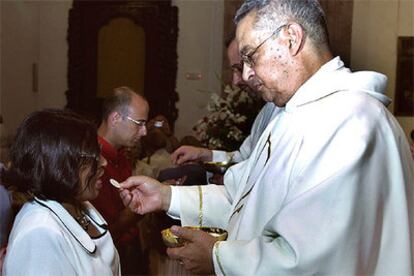 El ex pastor anglicano Evans David Gliwitzki da la comunión a su esposa, Patricia, durante su ordenación.