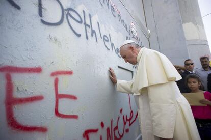 Francisco toca el muro que separa Cisjordania de Israel durante su visita a Belén.