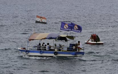 Dos banderas del Real Madrid y una bandera de Siria con una imagen del presidente Bachar El Asad ondean en una barca que navega en la costa de Latakia, Siria.