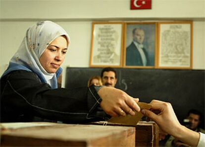 Una mujer turca vota ayer en Ankara. Al fondo, un retrato de Ataturk, el fundador de la Turquía moderna.