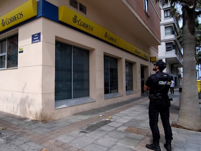 Un agente de la policía nacional hace guardia frente a la puerta de las oficinas de Correos en Melilla. sin colas, durante la campaña de voto por correo para el 28-M, este jueves.