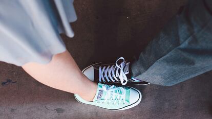 Dos personas con zapatillas Converse juntan sus pies