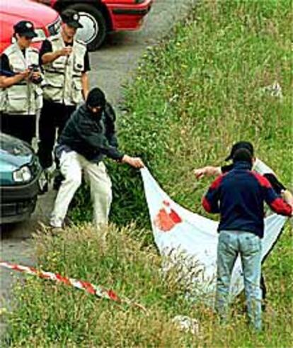 Miembros de la Erzaintza cubren con una sábana el cadáver de Santiago Oleaga.