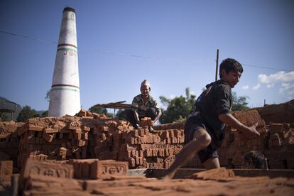 Un hombre y un chico trabajan en una de las muchas fábricas de ladrillos existentes en Katmandú (Nepal).