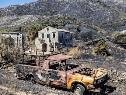 Turistas (al fondo) paseaban el viernes por los restos del incendio en Palia Pericia, una localidad muy afectada por el fuego, que solía ser una importante atracción turística.
