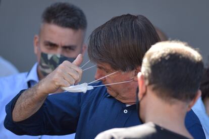 El presidente de Brasil, Jair Bolsonaro, se quita la mascarilla mientras sale de una tienda de motocicletas, en Brasilia (Brasil). Bolsonaro, de 65 años, ha dado negativo en un nuevo examen de coronavirus, una enfermedad que le fue detectada el pasado 7 de julio y que le mantuvo recluido en su residencia oficial hasta este sábado. "RT-PCR para SARS-CoV 2: negativo. Buen día a todos", escribió el propio Bolsonaro este sábado en sus redes sociales, bajo una foto en la que aparece sonriente y con una caja de hidroxicloroquina en la mano.