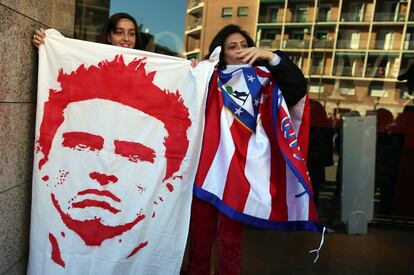 Unas aficionadas sujetan una bandera con la imagen de Fernando Torres en el exterior del estadio del Atlético de Madrid.