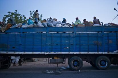 Camión en la ruta dirección al desierto. El remolque va cargado de sacos de grano sobre los que viajan los pasajeros.