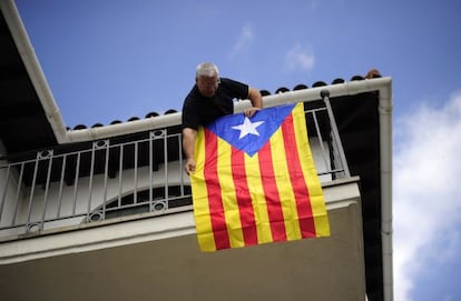 A man hangs a "Senyera", the Independentist flag at his balcony in Sant Pere de Torrello, near Barcelona Monday.
