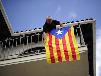 A man hangs a &quot;Senyera&quot;, the Independentist flag at his balcony  in Sant Pere de Torrello, near Barcelona Monday.