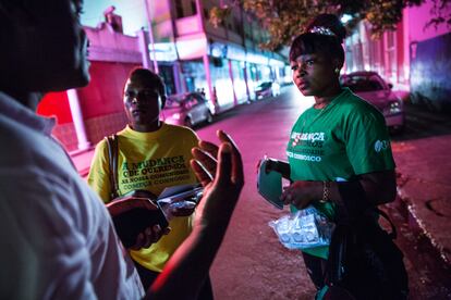 Armados con listas de mujeres para contactar, dos trabajadoras comunitarias hablan con personas en el distrito de luz roja del puerto de Maputo, Mozambique, para brindar información sobre prevención y derivación del VIH a quienes la necesitan.