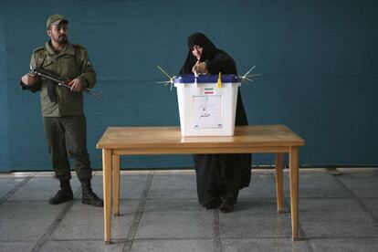 Una mujer vota en presencia de un policía e nun colegio electoral de Qom.