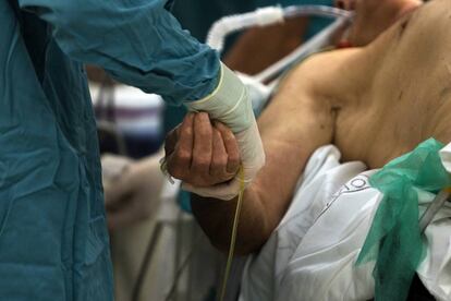 Un enfermero sostiene la mano de un paciente en el hospital Cl&iacute;nico de Barcelona.