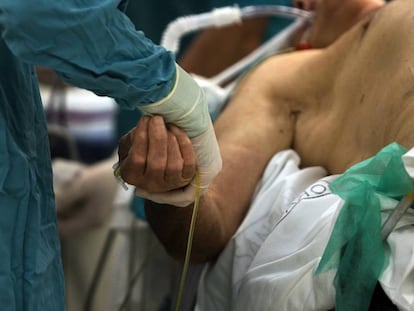 Un enfermero sostiene la mano de un paciente en el hospital Cl&iacute;nico de Barcelona.