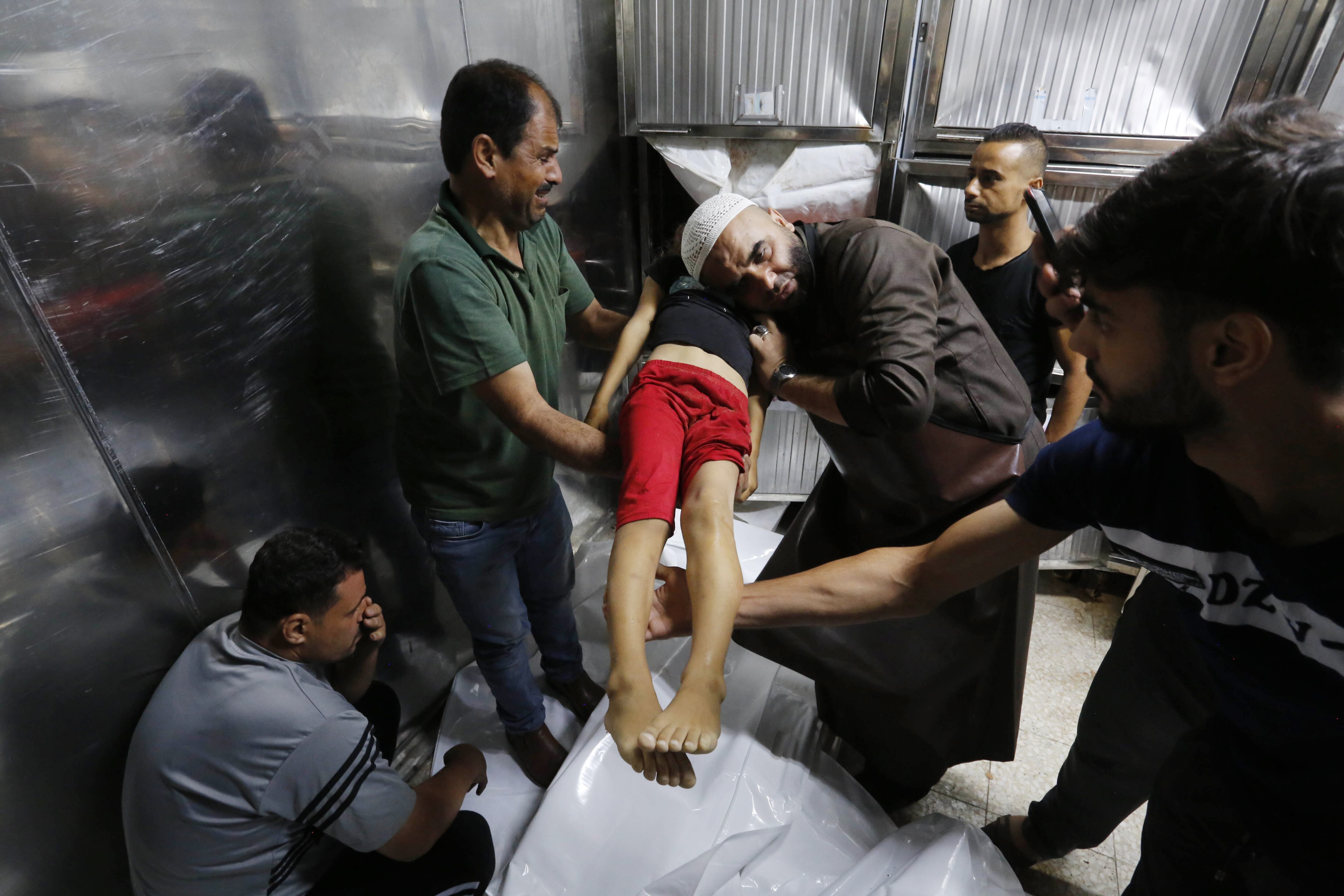 El cuerpo de una niña palestina, que murió en los ataques isralíes, es trasladada a la morgue del hospital Al-Shifa de Gaza, este lunes.