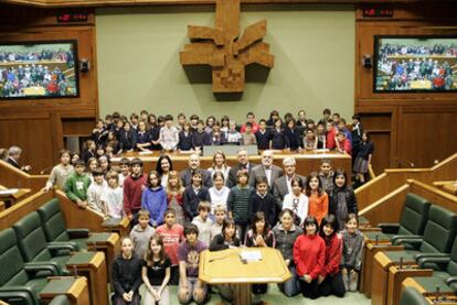 Los 75 escolares que participaron en la iniciativa posan en el salón de plenos del Parlamento junto a su presidenta, Arantza Quiroga (en la parte inferior de la sala, en el centro), y el resto de miembros de la Mesa de la Cámara.