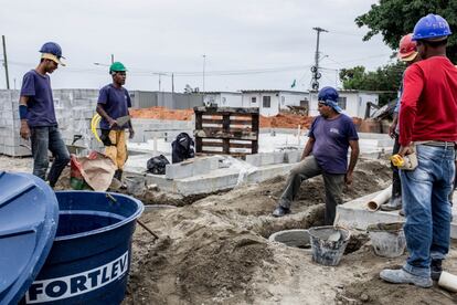 Obreros trabajando en las 20 casas que las familias tienen que recibir este verano para dejar de vivir en contenedores.