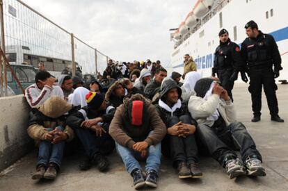 Inmigrantes tunecinos llegados a la isla italiana de Lampedusa esperan para ser trasladados a un centro de internamiento.