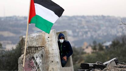 Manifestante palestino se refugia em um bloco de concreto.