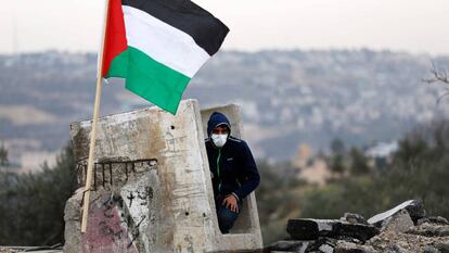 Manifestante palestino se refugia em um bloco de concreto.